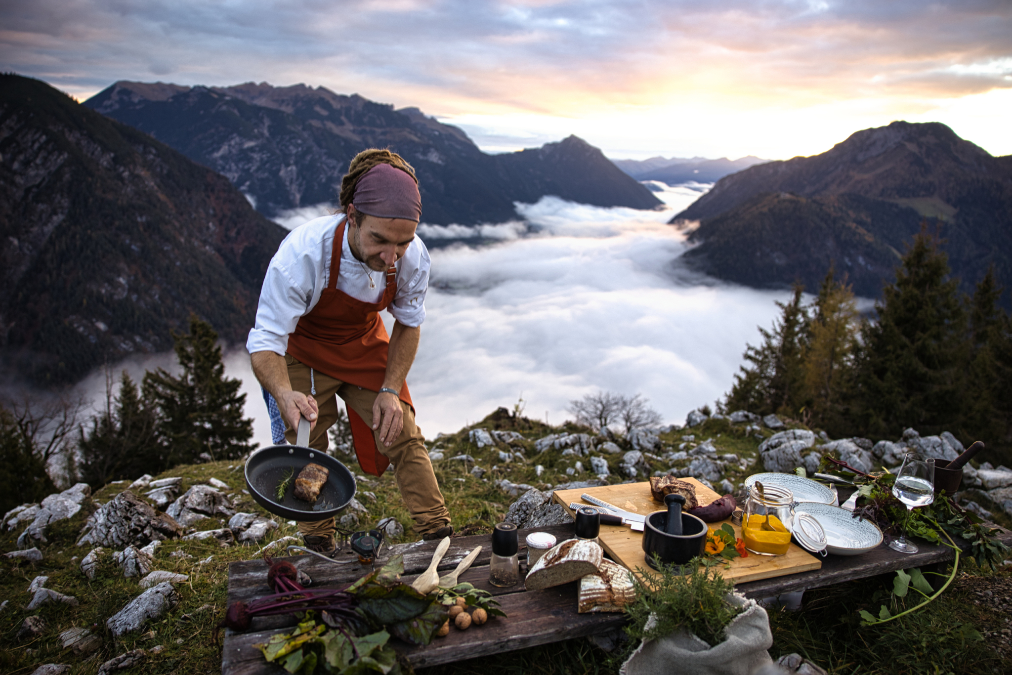 Koch beim kochen mitten auf einem Berg über den Wolken